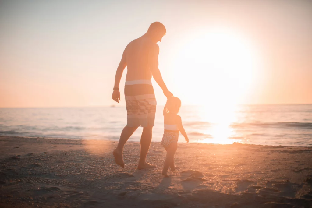 image d'un père et son enfant au bord de la mer face à un coucher de soleil pour symboliser le deuil d'un papa, d'un père
